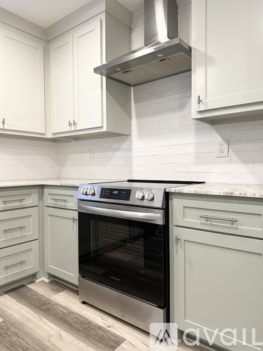 A modern kitchen with a stainless steel oven and white cabinets.