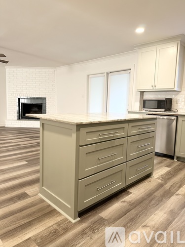 A kitchen with a white brick fireplace and wooden cabinets.