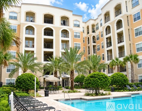 A large apartment complex with a pool and palm trees.