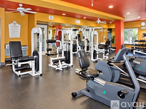 A gym with a variety of equipment including treadmills, weights, and a fan.