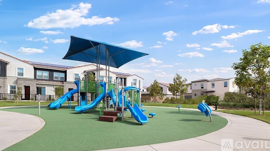A playground with a blue umbrella and a slide.