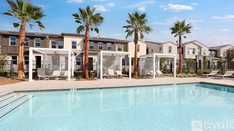 A swimming pool in front of a row of apartment buildings with palm trees.