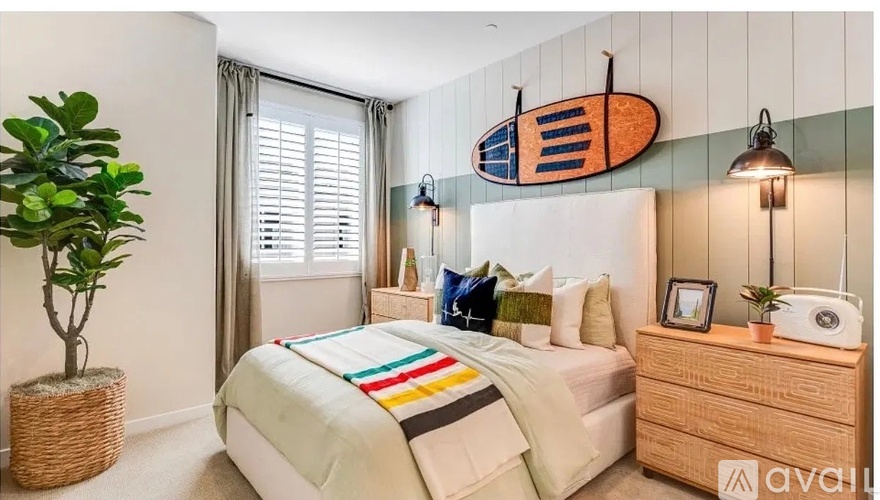 A bedroom with a bed, nightstand, and a plant.