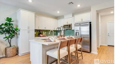 A kitchen with white cabinets and a wooden table set for four.