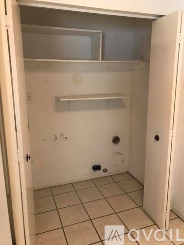 A small, empty kitchen with a white door and a white fridge.