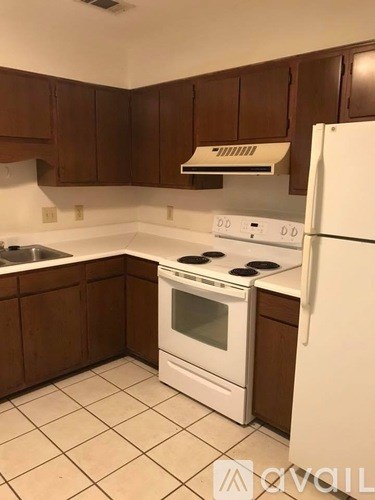 A kitchen with white appliances and brown cabinets.
