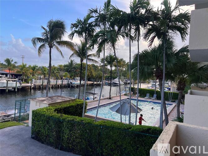 A pool surrounded by palm trees and a hedge.