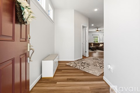 A hallway with a bench and a rug on the floor.