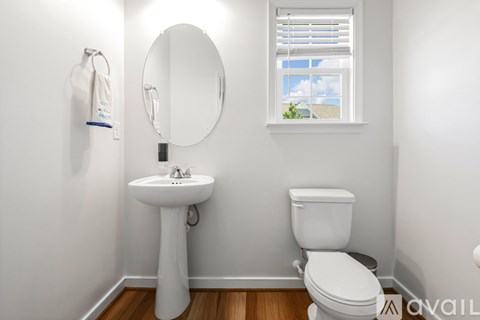 A white bathroom with a toilet, sink, and mirror.