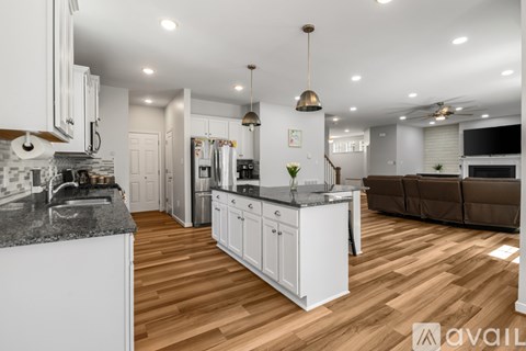 A modern kitchen with white cabinets and a wooden floor.