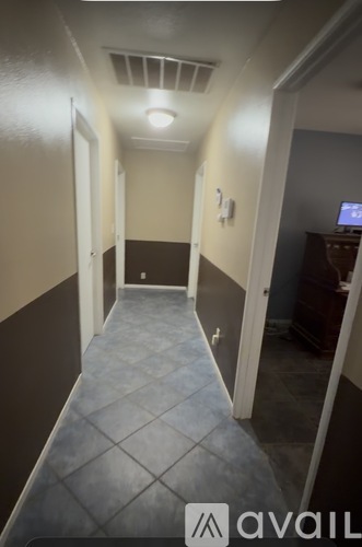 A long hallway with a tiled floor and a light on the ceiling.