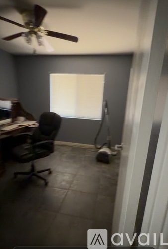 A room with a fan, a chair, and a window.