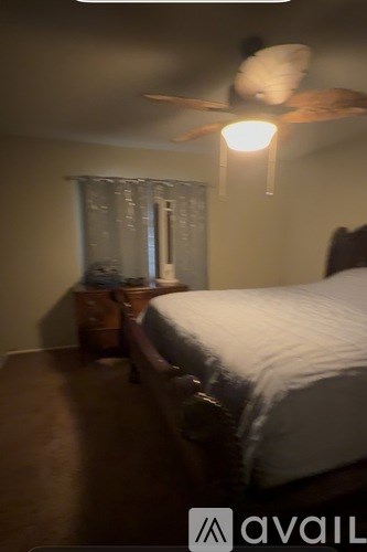 A bedroom with a bed, a ceiling fan, and a window with blinds.