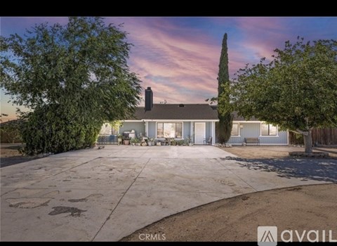 A house with a driveway and trees in front of it.