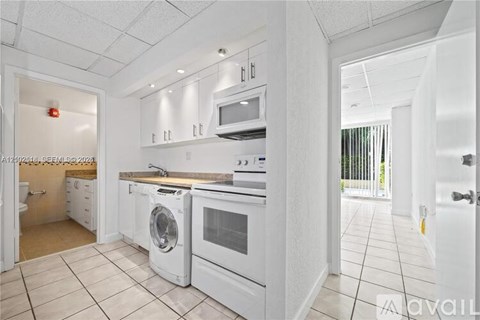 A white kitchen with a washing machine and a microwave.
