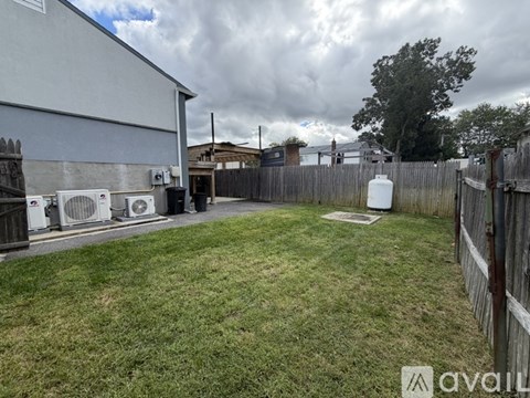 A backyard with a fence, a tree, and a building.