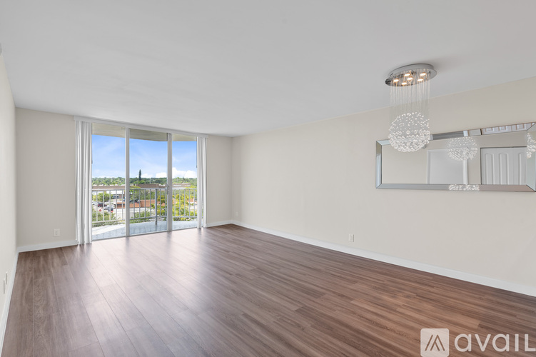 A room with wooden flooring and a large window overlooking a cityscape.