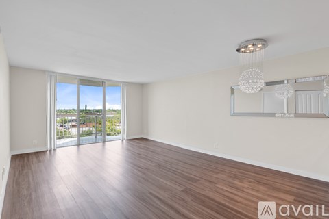 A room with wooden flooring and a large window overlooking a cityscape.