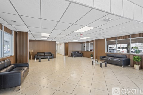 A spacious waiting area with black leather sofas and wooden paneling.