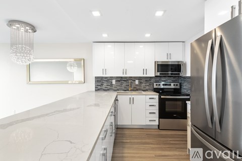A modern kitchen with a stainless steel refrigerator and white cabinets.