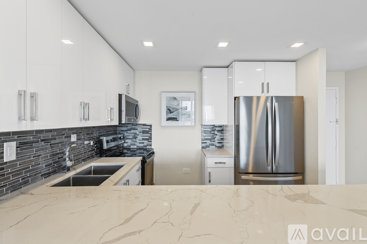 A modern kitchen with a marble countertop and stainless steel appliances.