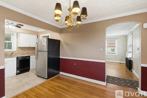 A kitchen with a black refrigerator and a chandelier hanging from the ceiling.
