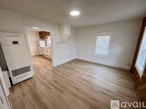A spacious room with wooden flooring and a window.