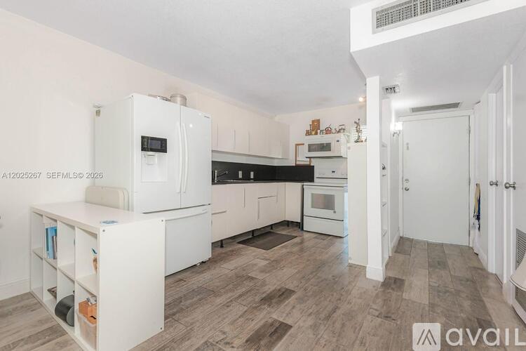 A kitchen with white appliances and wooden flooring.