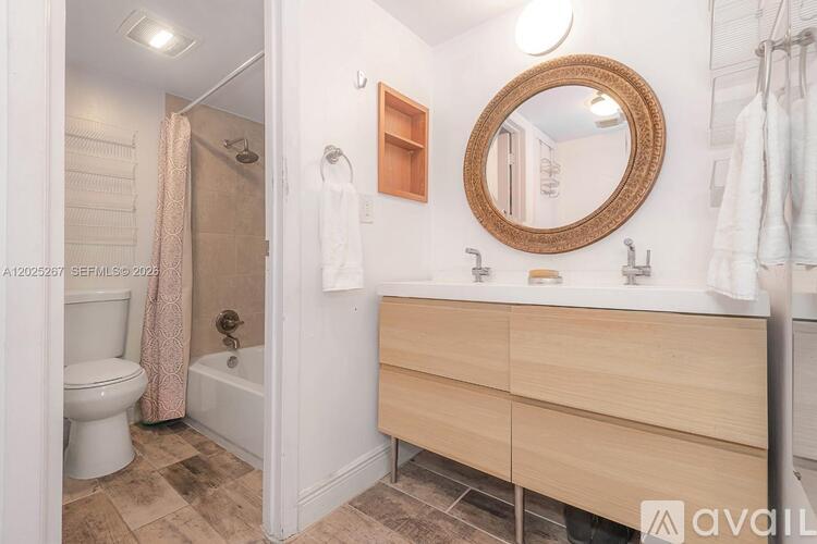 A bathroom with a wooden vanity and a round mirror.