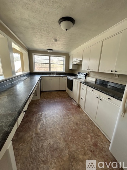 A kitchen with white cabinets and brown tiled floors.