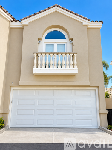 A beige house with a white garage door and a balcony with white railings.