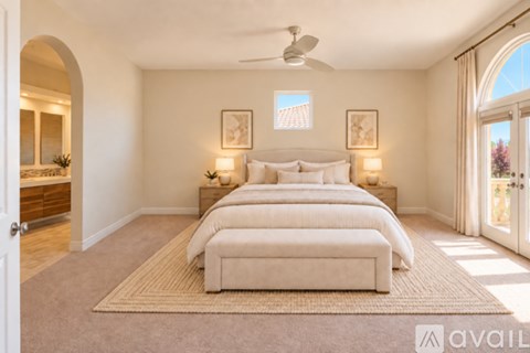 A bedroom with a large bed and a ceiling fan.