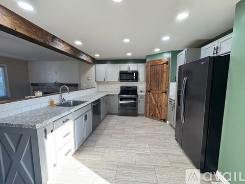 A kitchen with a black refrigerator and a wooden door cabinet.