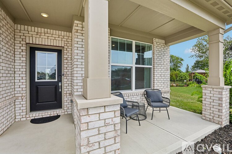 A patio with a black chair and a black door.