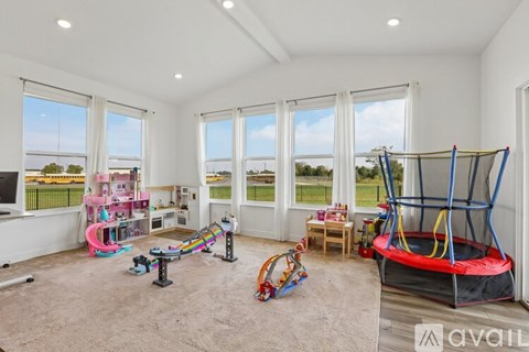 A spacious room with a trampoline, a slide, and a play area for children.