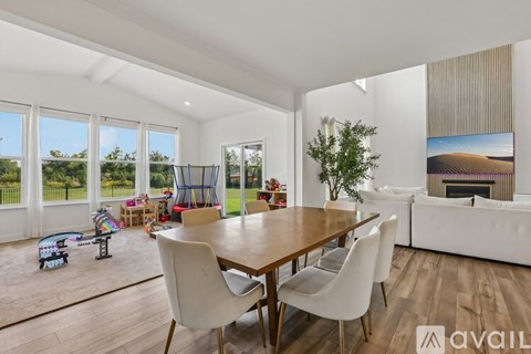 A modern dining room with a wooden table and white chairs.