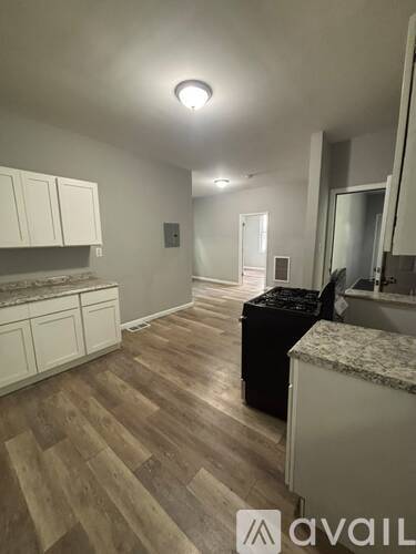 A kitchen with wooden floors and white cabinets.