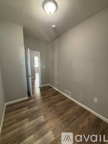 A room with wooden flooring and a doorway leading to another room.