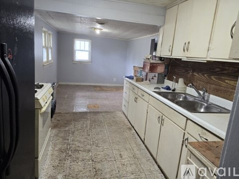 A kitchen with a refrigerator on the left and a sink in the middle.