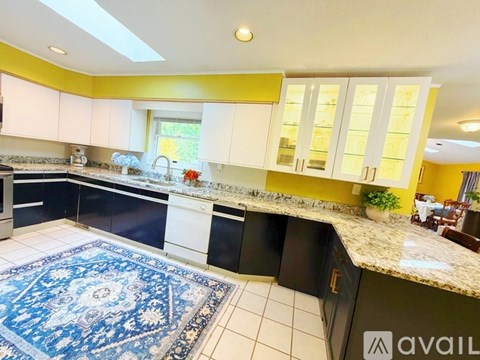 A kitchen with black and white cabinets and a blue rug on the floor.