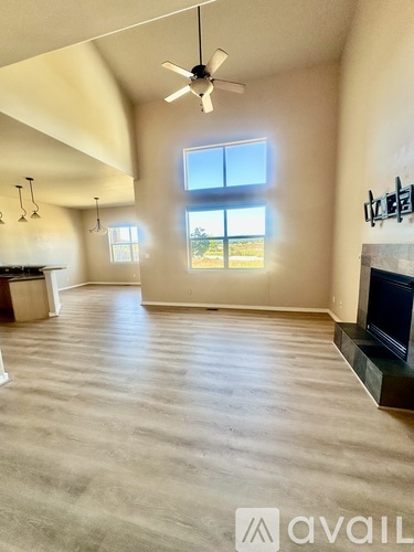 A spacious living room with a fireplace and a ceiling fan.