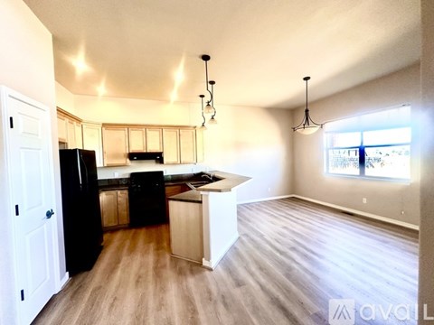 A kitchen with a black fridge and wooden floors.