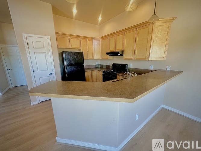 A kitchen with wooden cabinets and a black refrigerator.