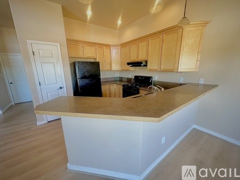A kitchen with wooden cabinets and a black refrigerator.