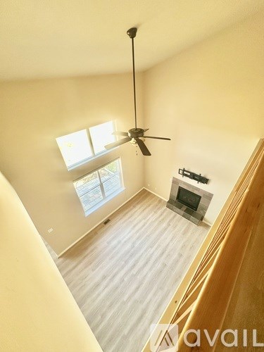 A living room with a fireplace and a ceiling fan.