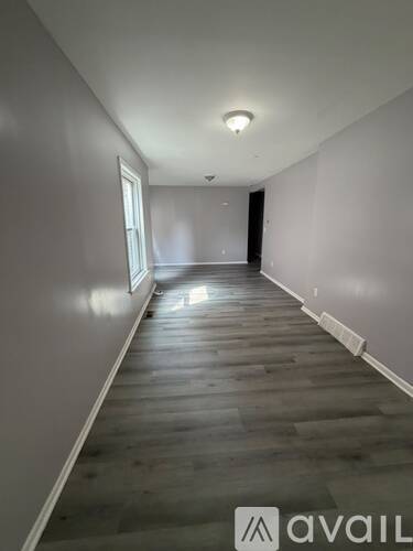 A long hallway with wooden floors and white walls.