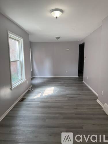 A room with wooden floors and a window on the left side.