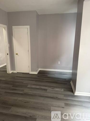 A room with a white door and wooden flooring.