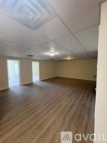 A room with wooden flooring and a white ceiling with recessed lighting.
