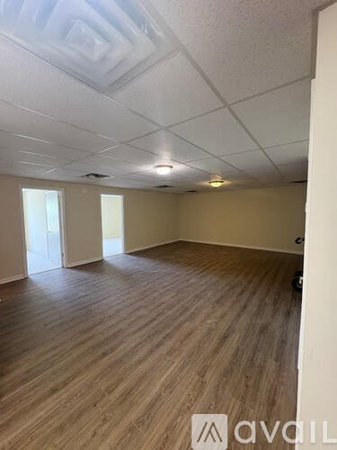 A room with wooden flooring and a white ceiling with recessed lighting.